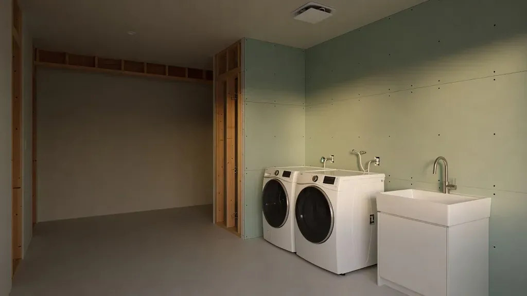Moisture-resistant drywall installed behind laundry appliances and a utility sink